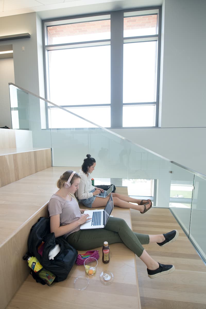 Students sitting on the stairs working on laptops