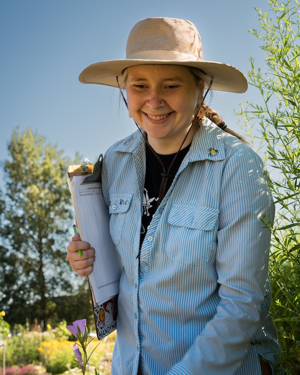 Jen Hayes holding a clipboard in the research garden plots