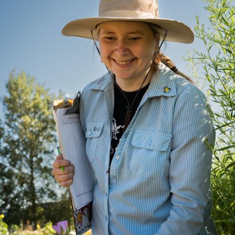 Jen Hayes holding a clipboard in the research garden plots